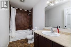 Bathroom with vanity, stone finish floors, shower / bath combo with shower curtain, and a textured ceiling - 