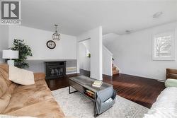 Living area with a glass covered fireplace, dark wood finished floors, and stairs - 