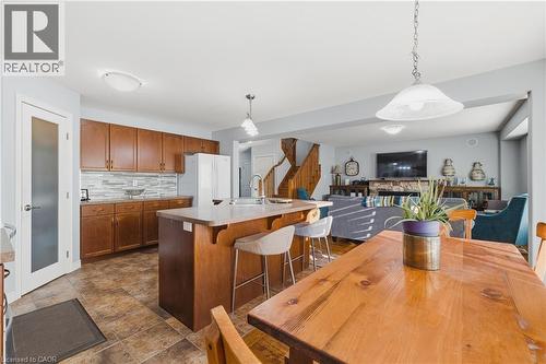 Kitchen with pendant lighting, brown cabinetry, a kitchen breakfast bar, and light countertops - 23 Doon Creek Street, Kitchener, ON - Indoor