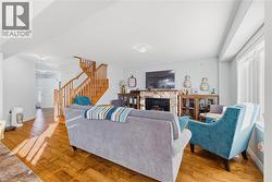 Living area featuring a stone fireplace, stairway, and light wood-style floors - 