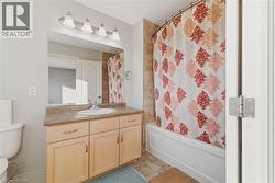 Full bath featuring vanity, shower / tub combo, and light tile patterned floors - 