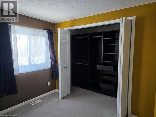 Unfurnished bedroom featuring light colored carpet, a textured ceiling, and a closet - 220 Snowdrop Crescent, Kitchener, ON - Indoor