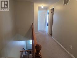 Hallway featuring an upstairs landing, light colored carpet, and a textured ceiling - 