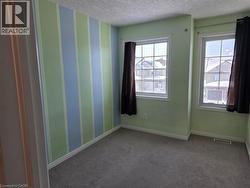 Empty room featuring carpet, a textured ceiling, and wallpapered walls - 