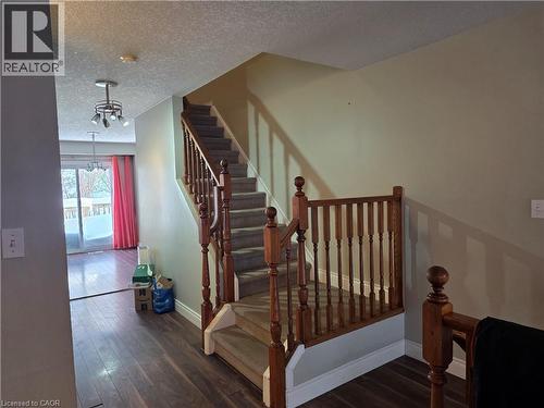 Staircase with hardwood / wood-style floors, a textured ceiling, and hanging lights - 220 Snowdrop Crescent, Kitchener, ON - Indoor Photo Showing Other Room