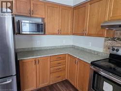 Kitchen featuring stainless steel appliances, wood finish cabinetry, light countertops, and tasteful backsplash - 