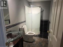 Bathroom with vanity, a shower stall, and dark stone finish floors - 