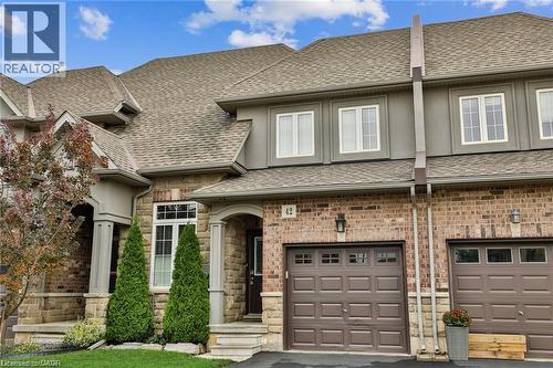 View of front facade featuring a shingled roof, an attached garage, driveway, and stone siding - 42 Madonna Drive, Hamilton, ON - Outdoor With Facade