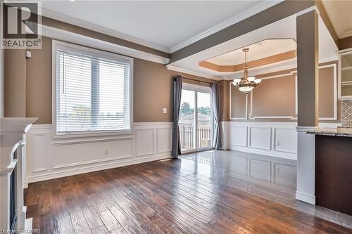 Unfurnished dining area featuring dark wood-style flooring, crown molding, a wainscoted wall, suspended lighting, and a tray ceiling - 42 Madonna Drive, Hamilton, ON - Indoor Photo Showing Other Room