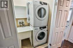 Laundry area featuring stacked washer / drying machine and tile patterned flooring - 