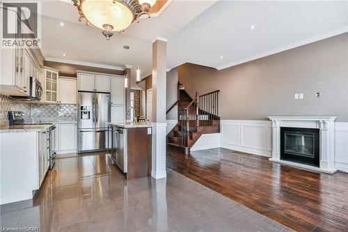 Kitchen featuring stainless steel appliances, glass fronted cabinets, pendant lighting, a glass covered fireplace, and light stone counters - 42 Madonna Drive, Hamilton, ON - Indoor Photo Showing Kitchen With Stainless Steel Kitchen With Upgraded Kitchen