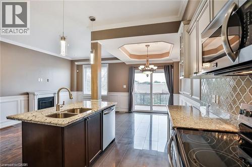 Kitchen featuring stainless steel appliances, light stone countertops, an island with sink, dark wood-style flooring, and a wainscoted wall - 42 Madonna Drive, Hamilton, ON - Indoor Photo Showing Kitchen With Double Sink