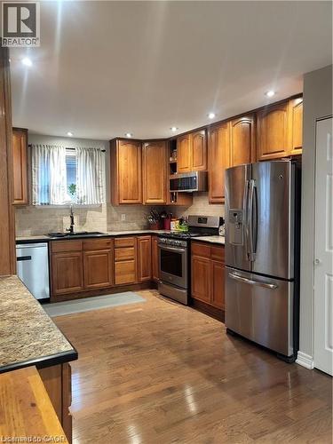 Kitchen with appliances with stainless steel finishes, brown cabinetry, wood finished floors, decorative backsplash, and recessed lighting - 18 Rosewell Street, Hamilton, ON - Indoor Photo Showing Kitchen With Stainless Steel Kitchen