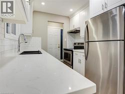 Kitchen with stainless steel appliances, white cabinetry, light stone counters, recessed lighting, and exhaust hood - 