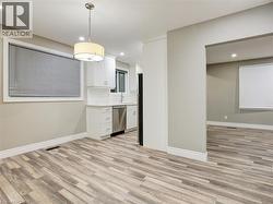 Kitchen featuring white cabinetry, hanging light fixtures, decorative backsplash, and light wood-style floors - 