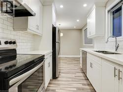 Kitchen featuring stainless steel appliances, white cabinets, pendant lighting, and backsplash - 