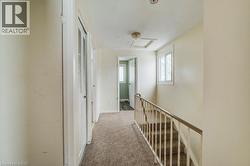 Hallway with carpet floors, attic access, a textured ceiling, and an upstairs landing - 