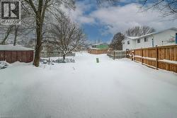 Yard layered in snow with a fenced backyard and a residential view - 