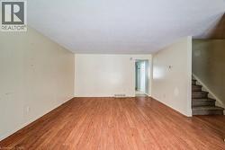 Unfurnished room featuring light wood-type flooring, stairs, and a textured ceiling - 
