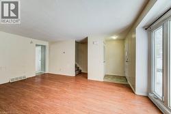 Unfurnished room with light wood-style flooring, stairway, a textured ceiling, and baseboard heating - 