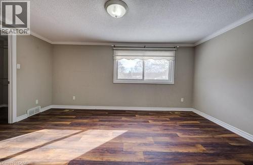 Empty room featuring dark wood finished floors, a textured ceiling, and ornamental molding - 54 Nicklaus Drive, Hamilton, ON - Indoor Photo Showing Other Room