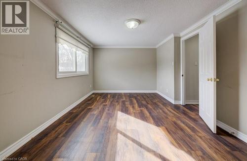 Unfurnished room featuring dark wood-style floors, ornamental molding, and a textured ceiling - 54 Nicklaus Drive, Hamilton, ON - Indoor Photo Showing Other Room