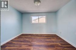Unfurnished room featuring dark wood-style flooring and a textured ceiling - 
