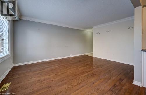 Spare room featuring crown molding, dark wood-type flooring, and a textured ceiling - 54 Nicklaus Drive, Hamilton, ON - Indoor Photo Showing Other Room