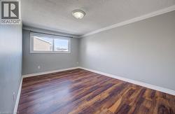 Unfurnished room with dark wood-type flooring, ornamental molding, and a textured ceiling - 