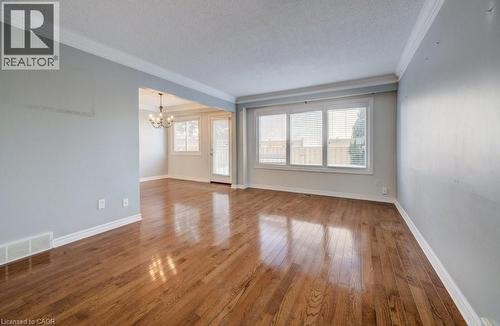 Unfurnished room with hardwood / wood-style floors, a textured ceiling, a chandelier, and crown molding - 54 Nicklaus Drive, Hamilton, ON - Indoor Photo Showing Other Room