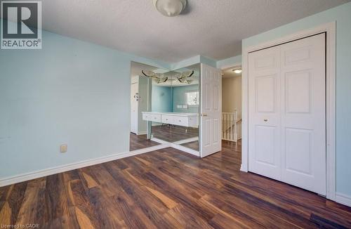 Unfurnished bedroom with a textured ceiling, dark wood-style floors, and a closet - 54 Nicklaus Drive, Hamilton, ON - Indoor Photo Showing Other Room