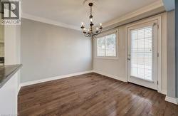 Unfurnished dining area with dark wood-style floors, a chandelier, and crown molding - 