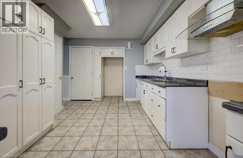 Kitchen with under cabinet range hood, white cabinetry, and tasteful backsplash - 54 Nicklaus Drive, Hamilton, ON - Indoor Photo Showing Kitchen