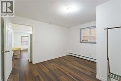 Unfurnished bedroom featuring baseboard heating, dark wood-style floors, and a baseboard heating unit - 