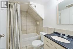 Bathroom with vanity, shower / tub combo with curtain, tile walls, and light tile patterned flooring - 