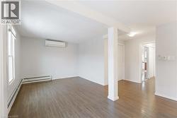 Unfurnished room featuring dark wood-style floors, a baseboard radiator, and a wall mounted AC - 