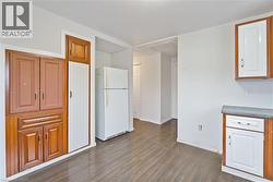 Kitchen with freestanding refrigerator, dark wood-style flooring, and brown cabinets - 