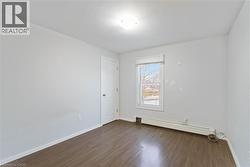 Spare room with dark wood-type flooring and a baseboard heating unit - 
