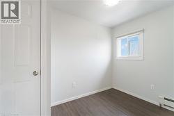 Unfurnished room featuring a baseboard heating unit and dark wood-style floors - 