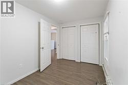 Unfurnished bedroom with two closets, a baseboard heating unit, and dark wood finished floors - 
