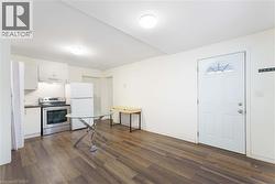 Kitchen featuring white cabinetry, electric range, freestanding refrigerator, dark wood-style floors, and under cabinet range hood - 