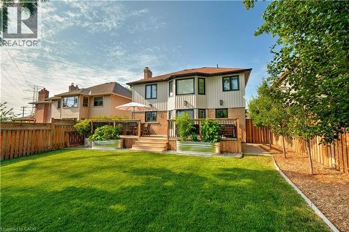 Back of house with brick siding, a wooden deck, a fenced backyard, and a chimney - 697 Lambshead Drive, Burlington, ON - Outdoor