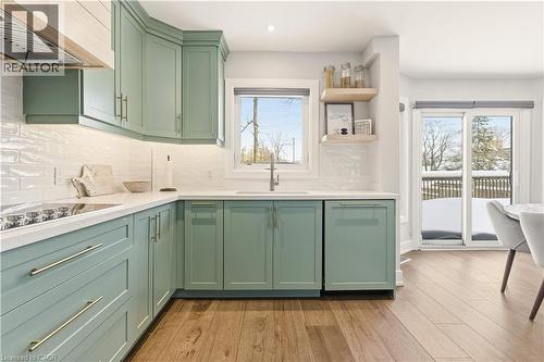 Kitchen featuring green cabinets, wall chimney range hood, light wood-type flooring, decorative backsplash, and recessed lighting - 697 Lambshead Drive, Burlington, ON - Indoor Photo Showing Kitchen