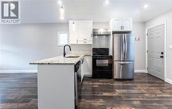 Kitchen featuring stainless steel appliances, backsplash, light stone counters, white cabinets, and recessed lighting - 