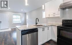 Kitchen featuring black / electric stove, tasteful backsplash, wall chimney range hood, dishwasher, and a peninsula - 