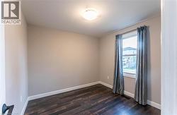 Empty room with baseboards and dark wood-style floors - 