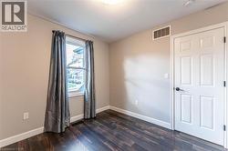 Spare room featuring dark wood-style floors and baseboards - 