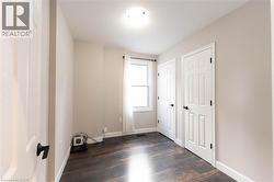 Unfurnished bedroom with baseboards and dark wood finished floors - 