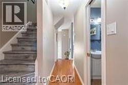 Hall with a barn door, stairs, wood finished floors, and baseboards - 