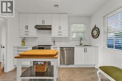 Kitchen with backsplash, stainless steel appliances, wooden ceiling, white cabinetry, and light stone counters - 